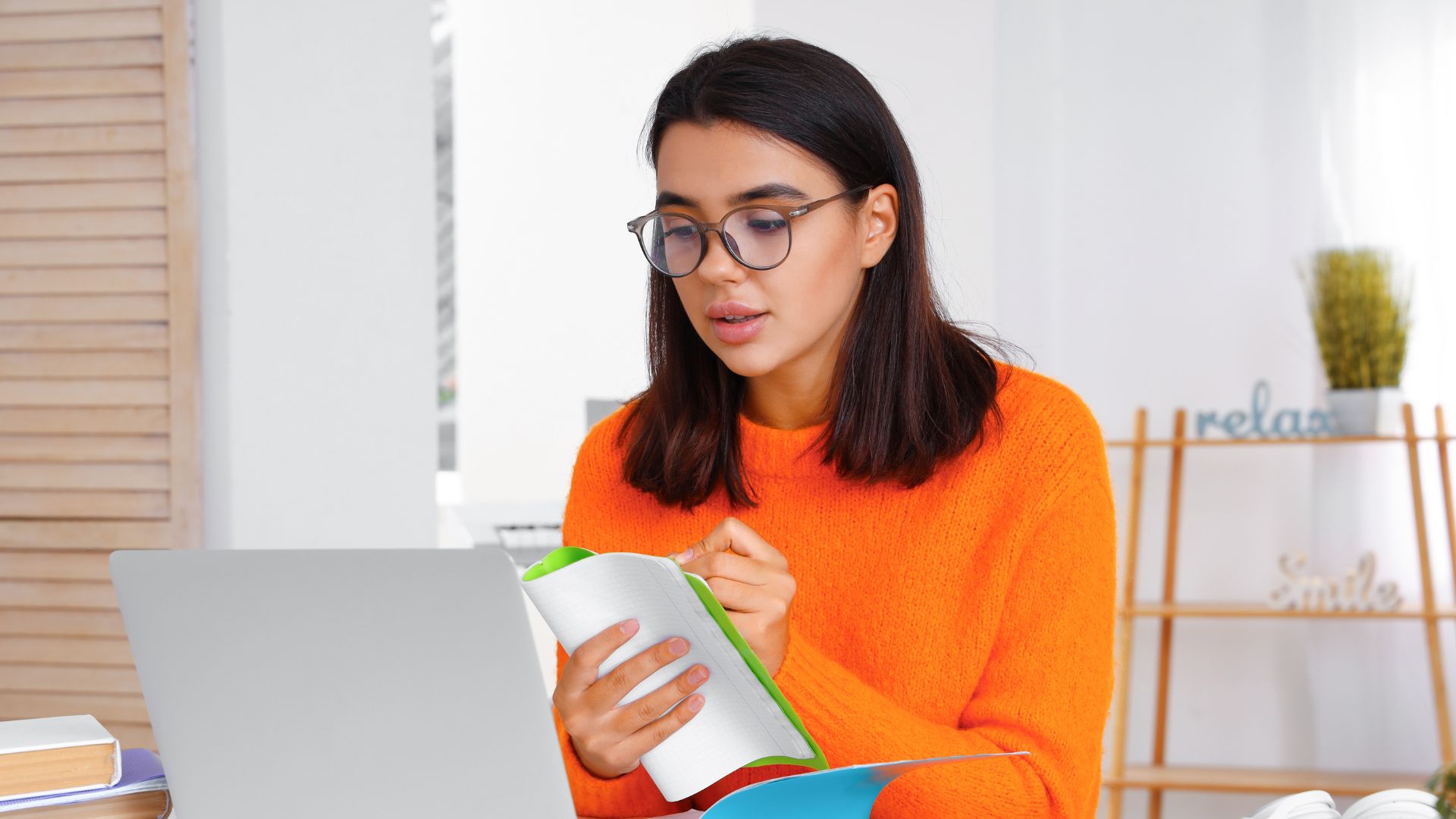 kobieta przed laptopem zapisująca coś w zeszycie